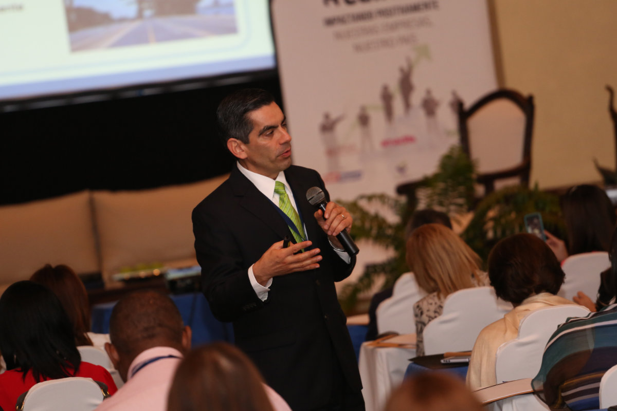 Conferencista en una actividad de Suprema Qualitas sosteniendo un micrófono mientras dicta una charla.